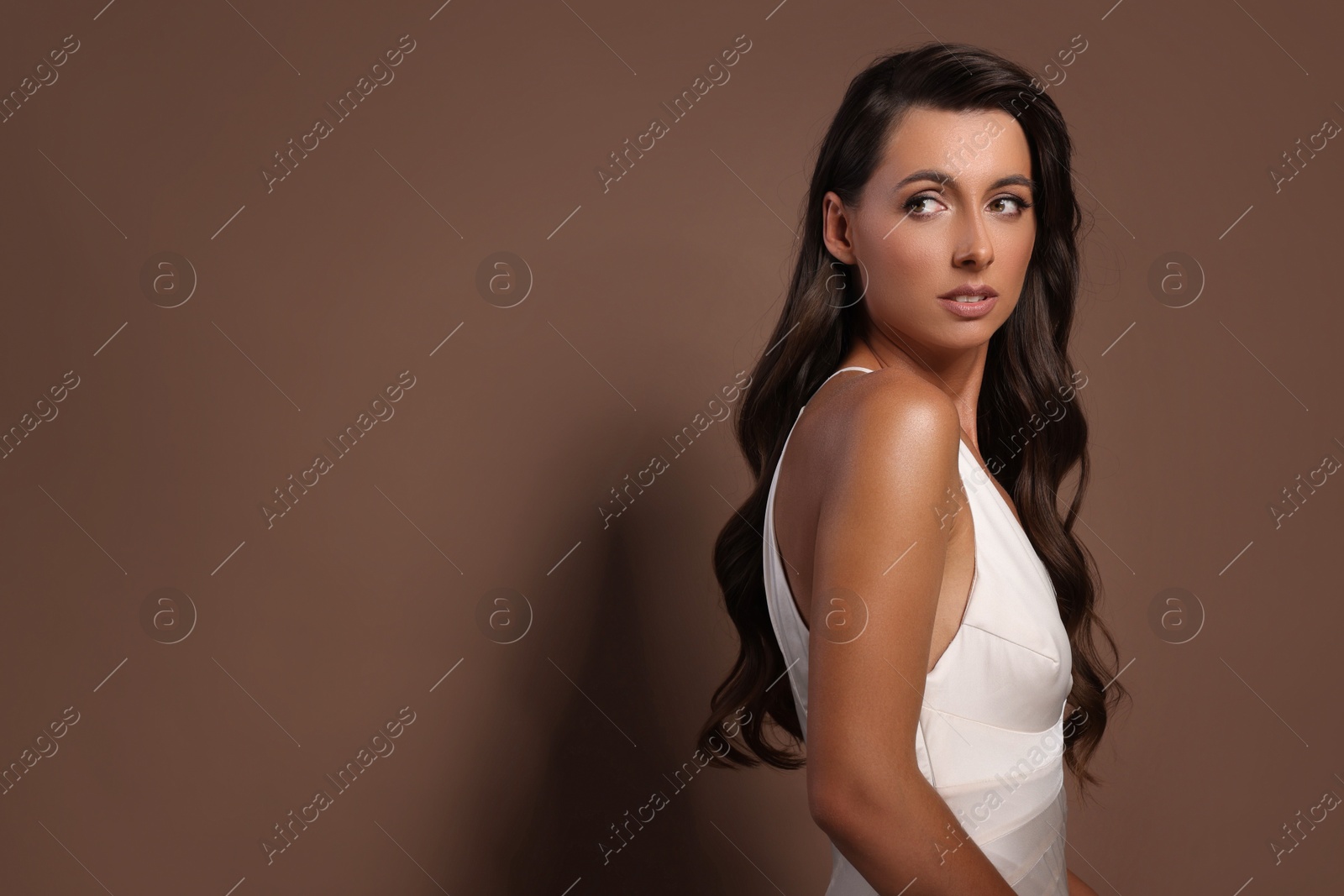 Photo of Hair styling. Beautiful woman with wavy long hair on brown background, space for text