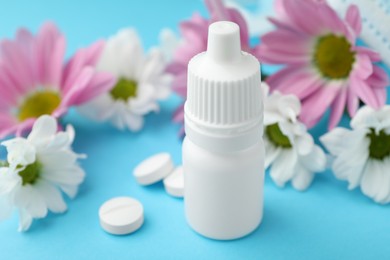 Photo of Allergy treatment. Nasal drops, pills and flowers on light blue background, closeup