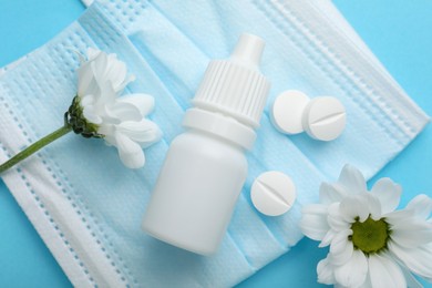 Photo of Allergy treatment. Nasal drops, pills, flowers and protective mask on light blue background, flat lay