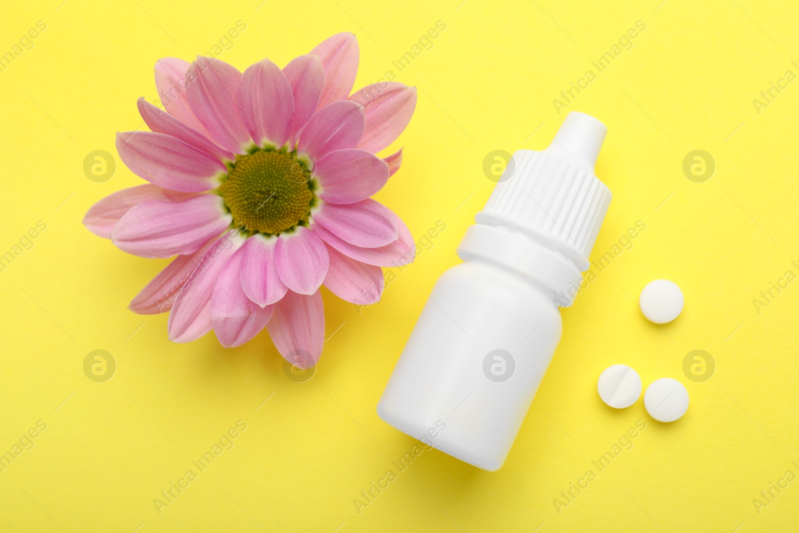 Photo of Allergy treatment. Nasal drops, pills and flower on yellow background, flat lay