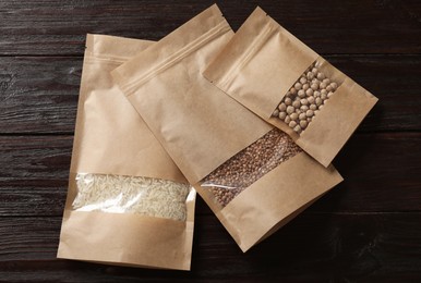 Photo of Paper pouch bags with buckwheat, chickpeas and rice on wooden table, flat lay