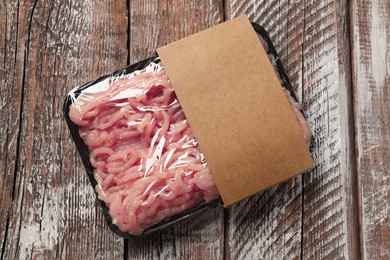 Photo of Plastic pack with fresh minced meat on rustic wooden table, top view