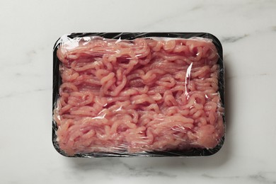 Photo of Plastic pack with fresh minced meat on white marble table, top view