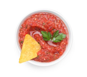 Photo of Delicious spicy salsa sauce with nacho chip in bowl isolated on white, top view