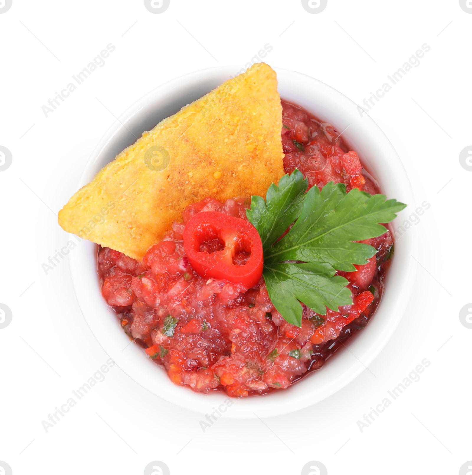 Photo of Spicy salsa sauce in bowl and nacho chip isolated on white, top view