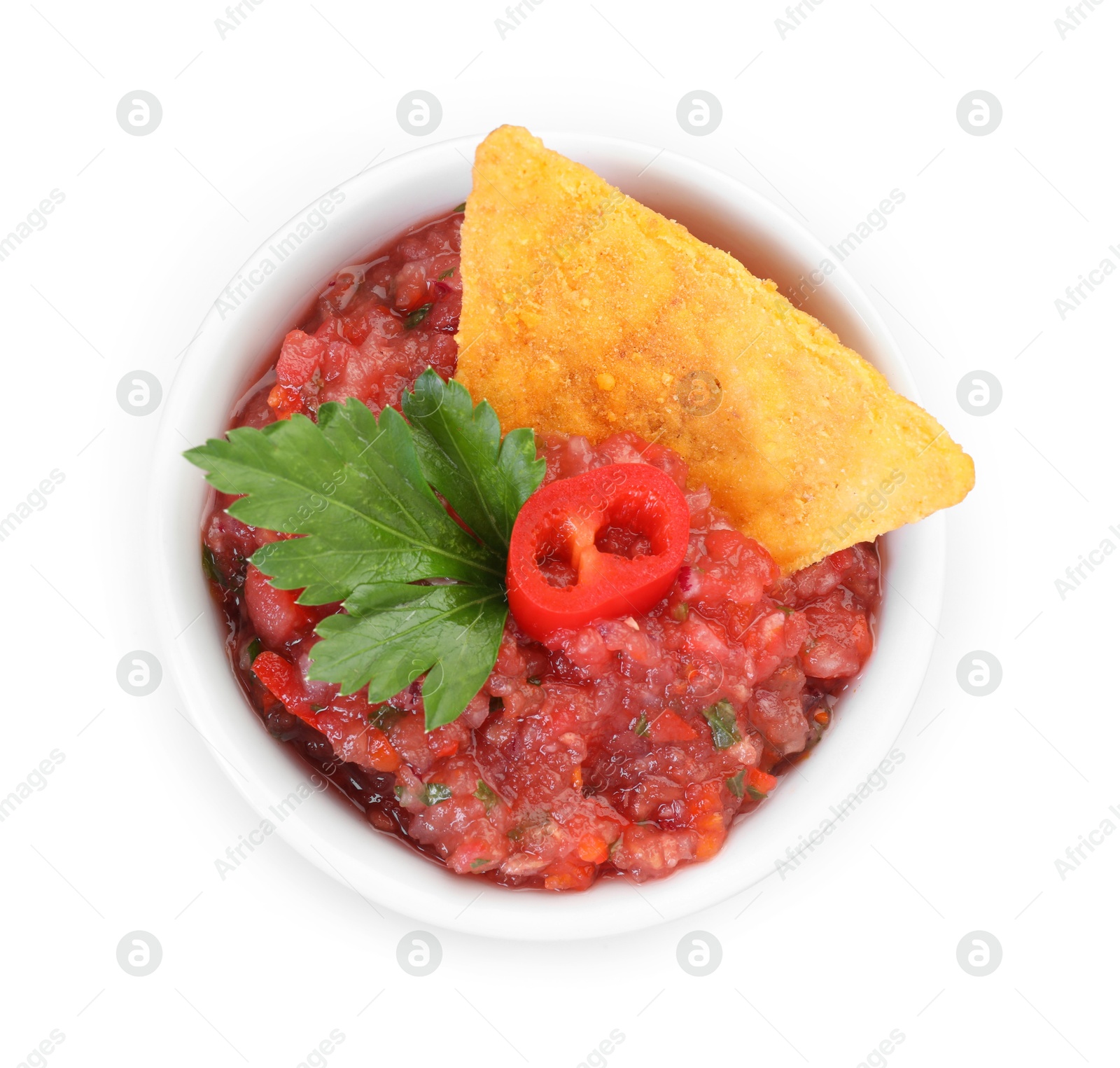 Photo of Spicy salsa sauce in bowl and nacho chip isolated on white, top view