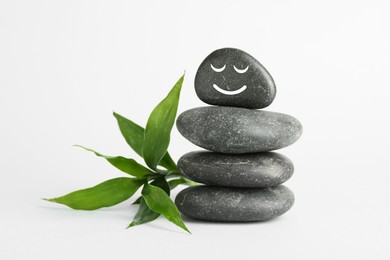 Photo of Stack of rocks with drawn smiley face on light background. Harmony and life balance