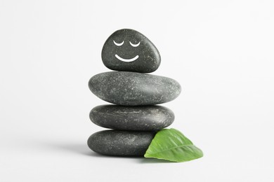 Photo of Stack of rocks with drawn smiley face on light background. Harmony and life balance