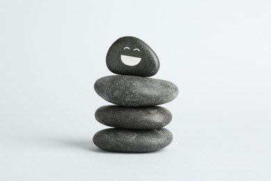 Photo of Stack of rocks with drawn smiley face on light background. Harmony and life balance