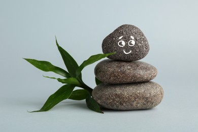 Photo of Stack of rocks with drawn smiley face on light grey background. Harmony and life balance