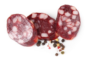 Photo of Pieces of delicious dry cured sausage and spices isolated on white, top view