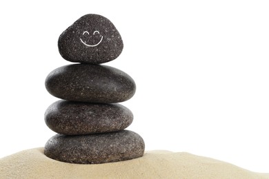 Photo of Stack of stones with drawn smiley face on sand against white background. Harmony and life balance