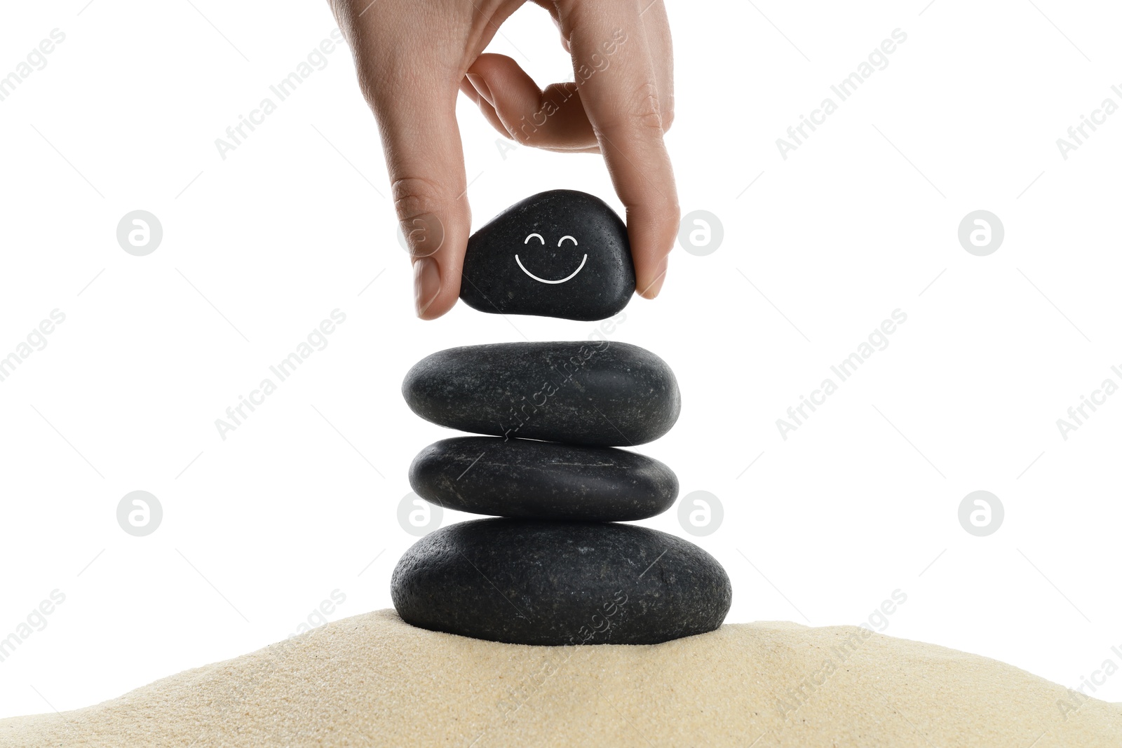 Photo of Woman putting stone with drawn smiley face on stack against white background, closeup. Harmony and life balance