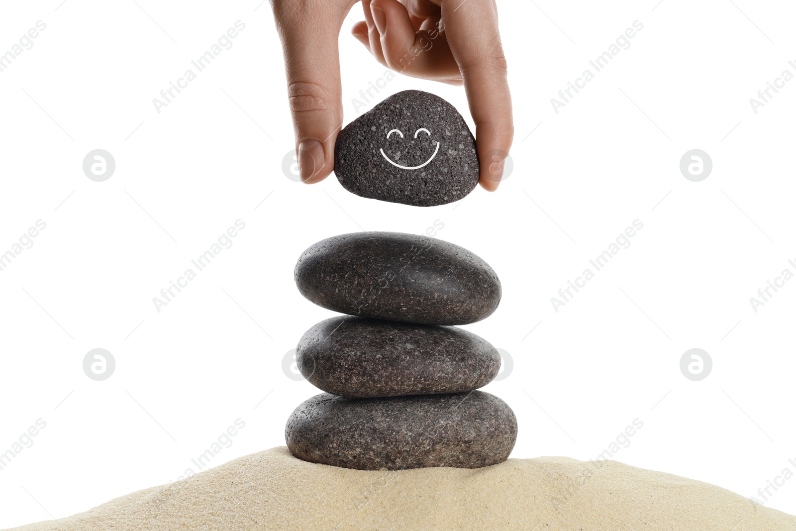 Photo of Woman putting stone with drawn smiley face on stack against white background, closeup. Harmony and life balance