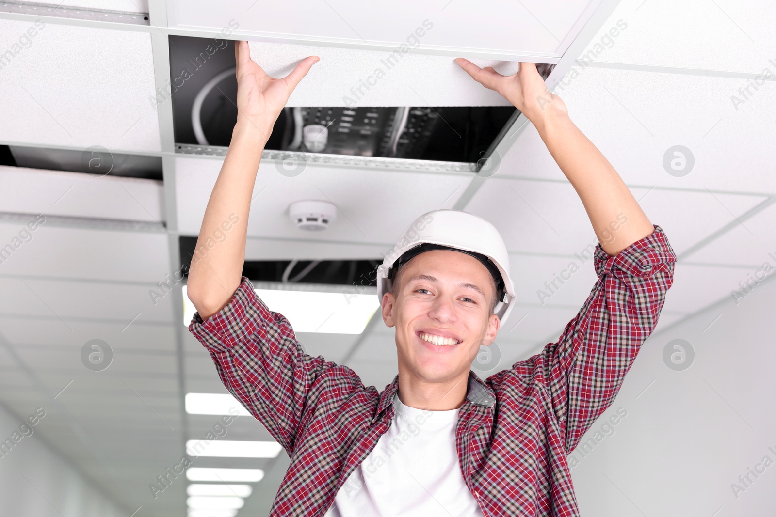 Photo of Suspended ceiling installation. Builder working with PVC tile indoors