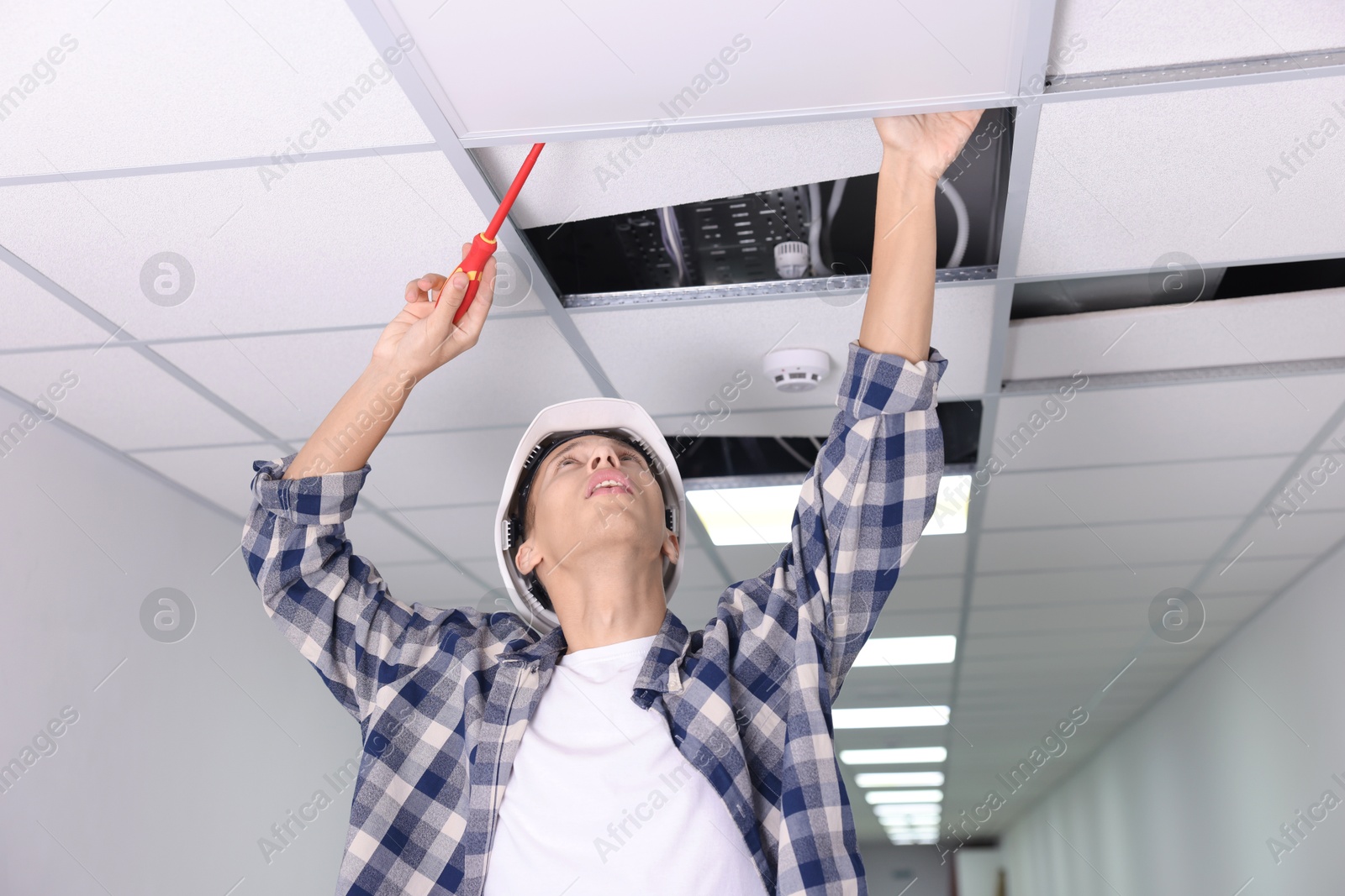 Photo of Suspended ceiling installation. Builder working with PVC tile indoors