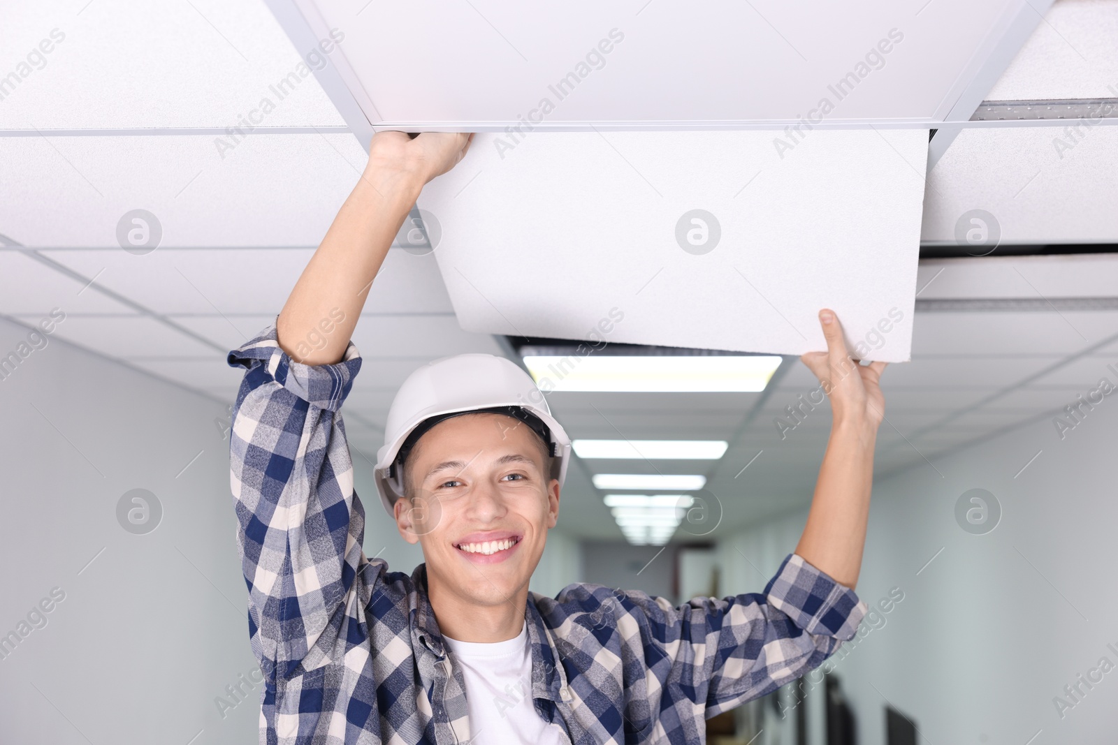 Photo of Suspended ceiling installation. Builder working with PVC tile indoors