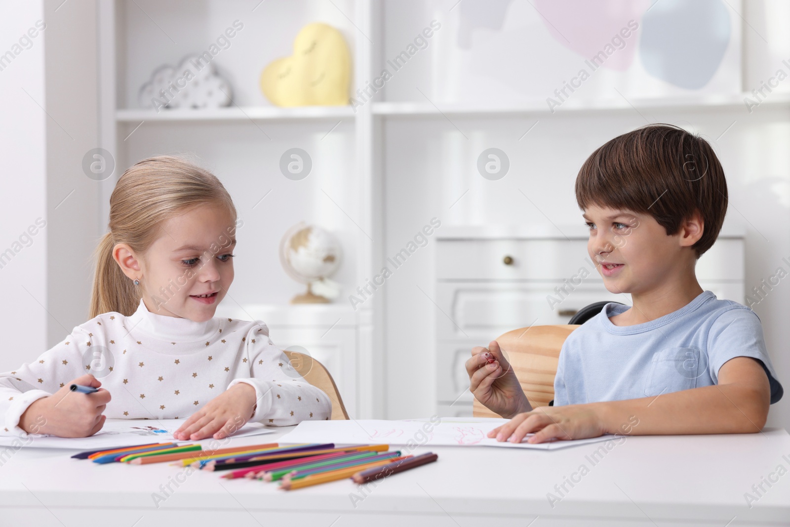 Photo of Cute children drawing at white table in kindergarten