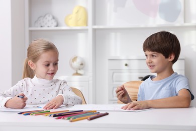 Photo of Cute children drawing at white table in kindergarten