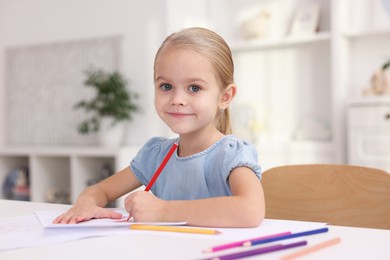 Photo of Portrait of cute girl drawing at white table in kindergarten