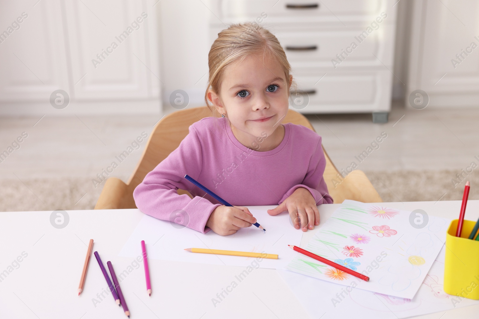 Photo of Cute girl drawing at white table in kindergarten