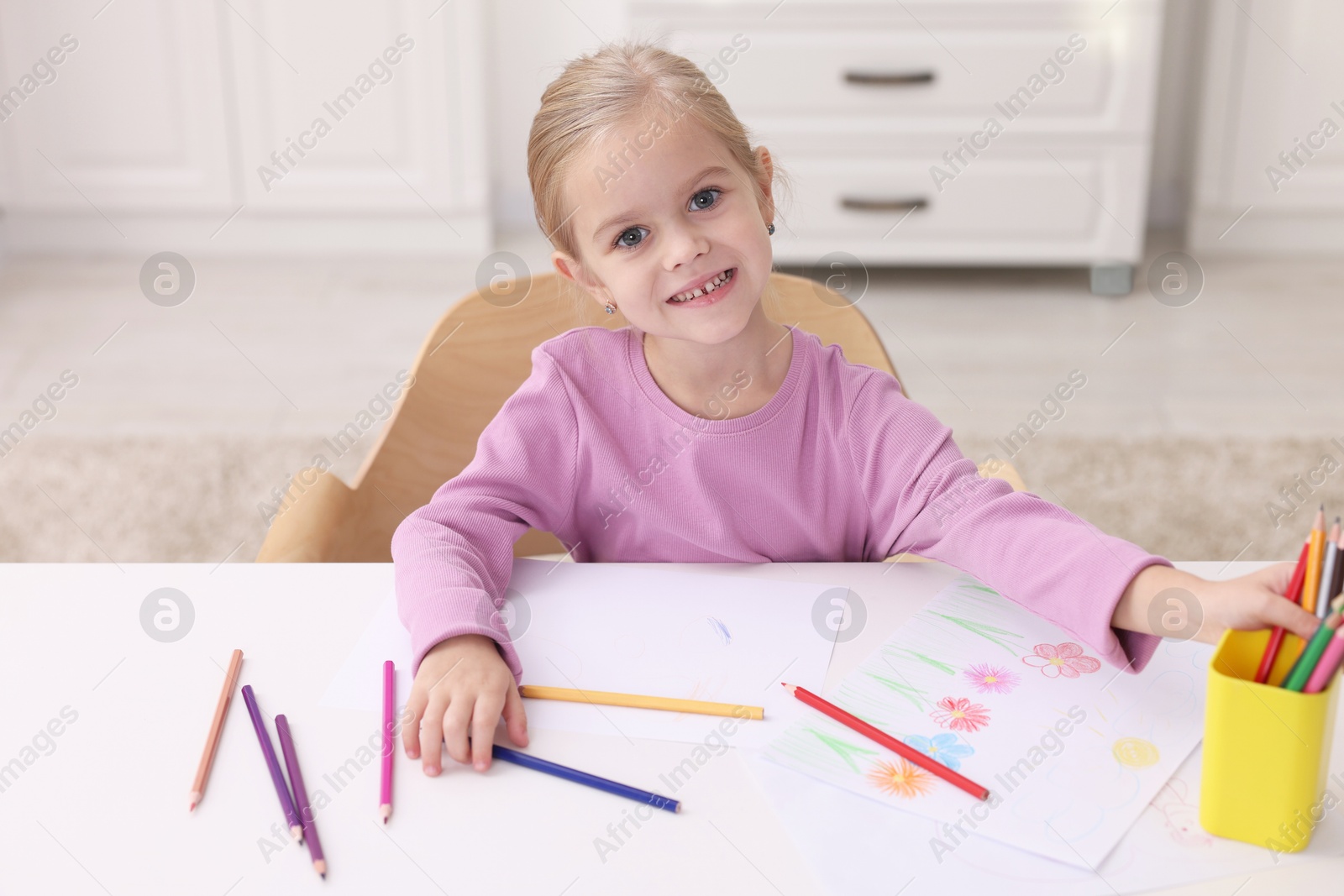 Photo of Smiling girl at white table with drawing in kindergarten