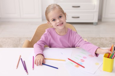 Photo of Smiling girl at white table with drawing in kindergarten