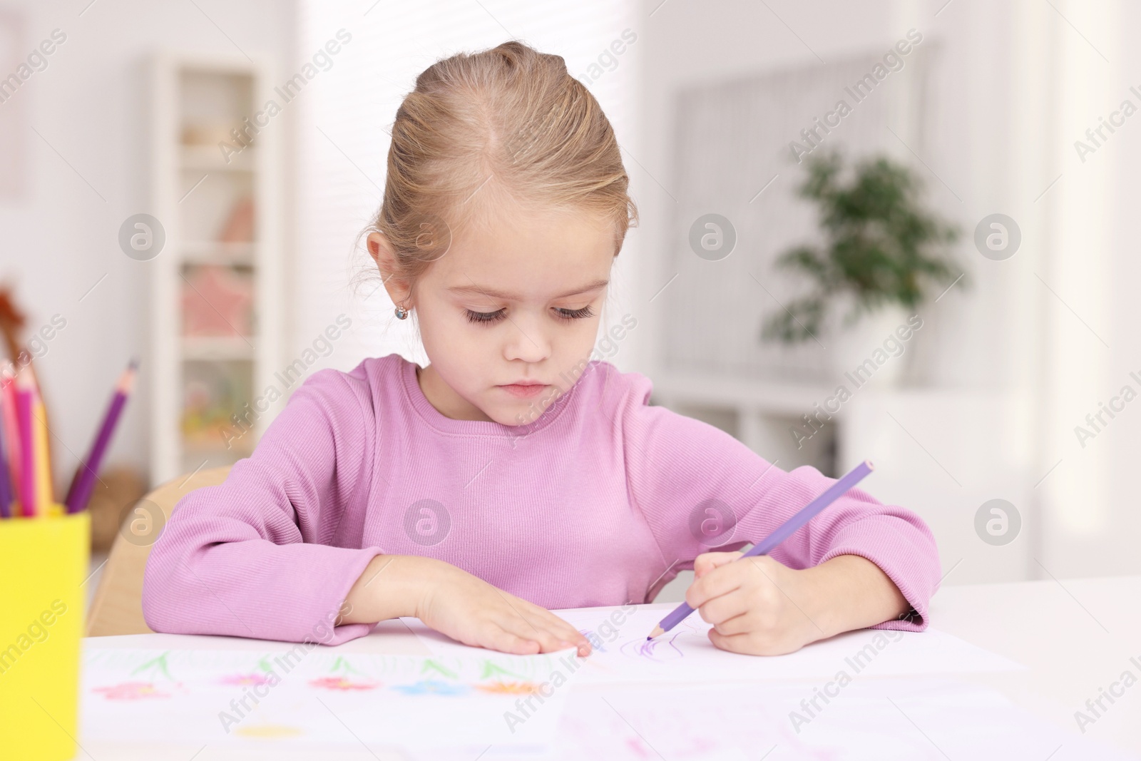 Photo of Cute girl drawing at white table in kindergarten