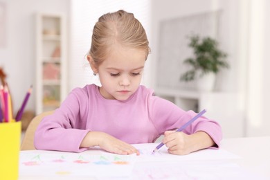 Photo of Cute girl drawing at white table in kindergarten