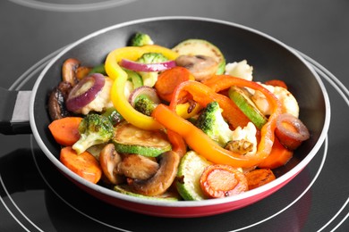 Photo of Frying pan with mix of vegetables and mushrooms on cooktop, closeup