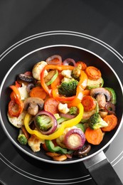 Photo of Frying pan with mix of vegetables and mushrooms on cooktop, top view