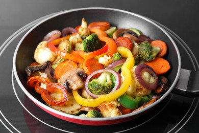 Photo of Frying pan with mix of vegetables and mushrooms on cooktop, closeup