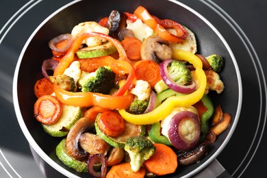 Photo of Frying pan with mix of vegetables and mushrooms on cooktop, closeup