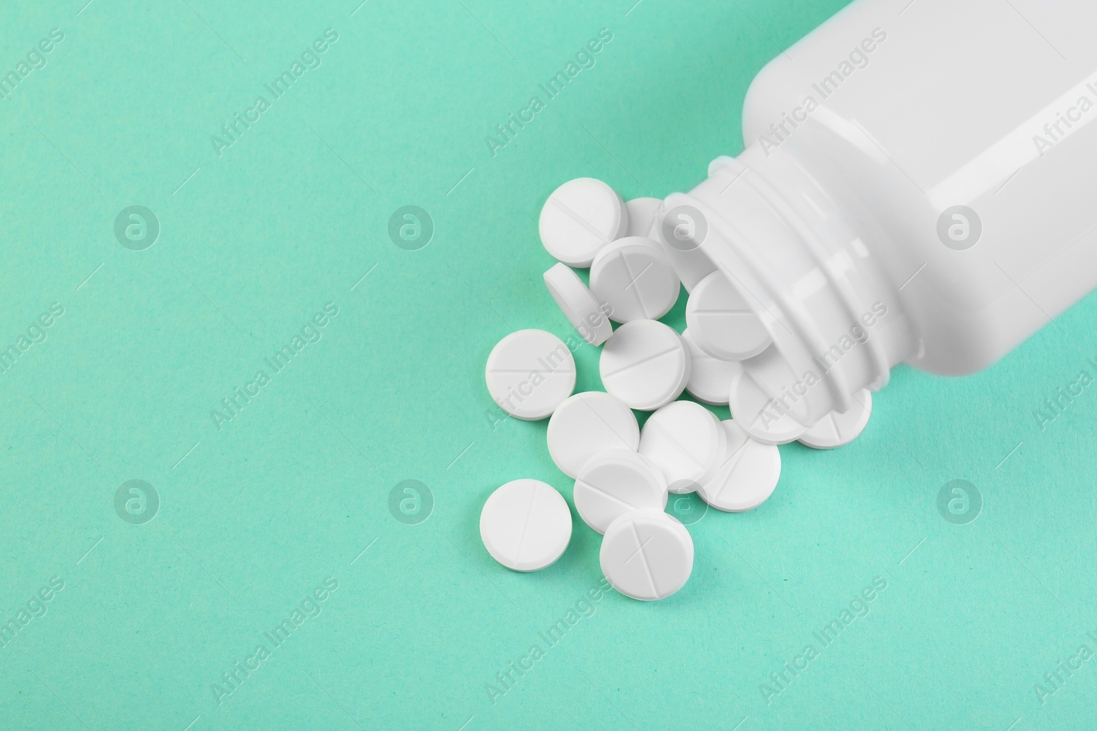 Photo of Bottle of antibiotic pills on turquoise background, top view. Space for text