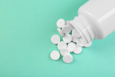 Photo of Bottle of antibiotic pills on turquoise background, top view. Space for text