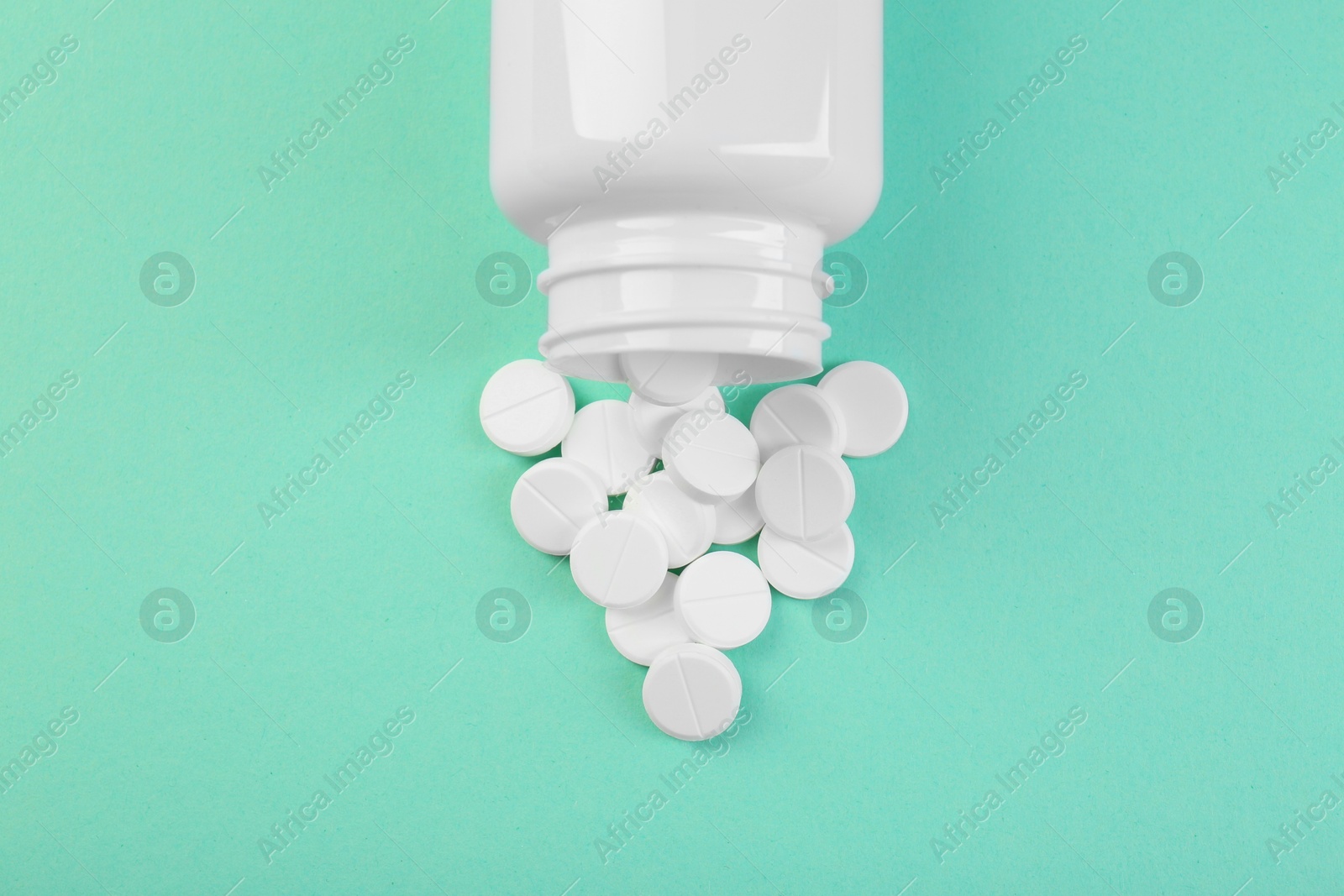 Photo of Bottle of antibiotic pills on turquoise background, top view