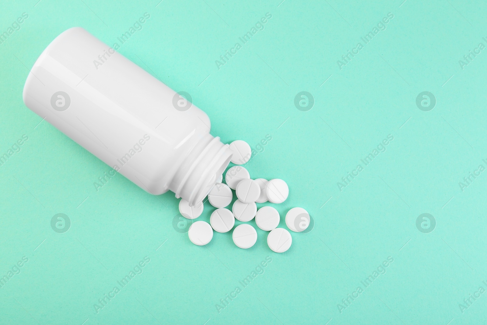 Photo of Bottle of antibiotic pills on turquoise background, top view. Space for text