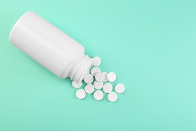 Photo of Bottle of antibiotic pills on turquoise background, top view. Space for text