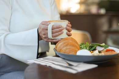 Photo of Woman having tasty breakfast in cafe, closeup