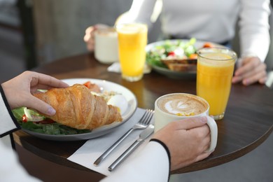 Photo of Women having tasty breakfast in cafe, closeup