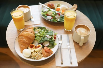 Photo of Tasty breakfast. Different meals and drinks served on wooden table in cafe