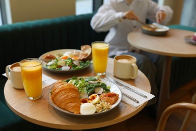 Photo of Woman having tasty breakfast in cafe, focus on different meals and coffee