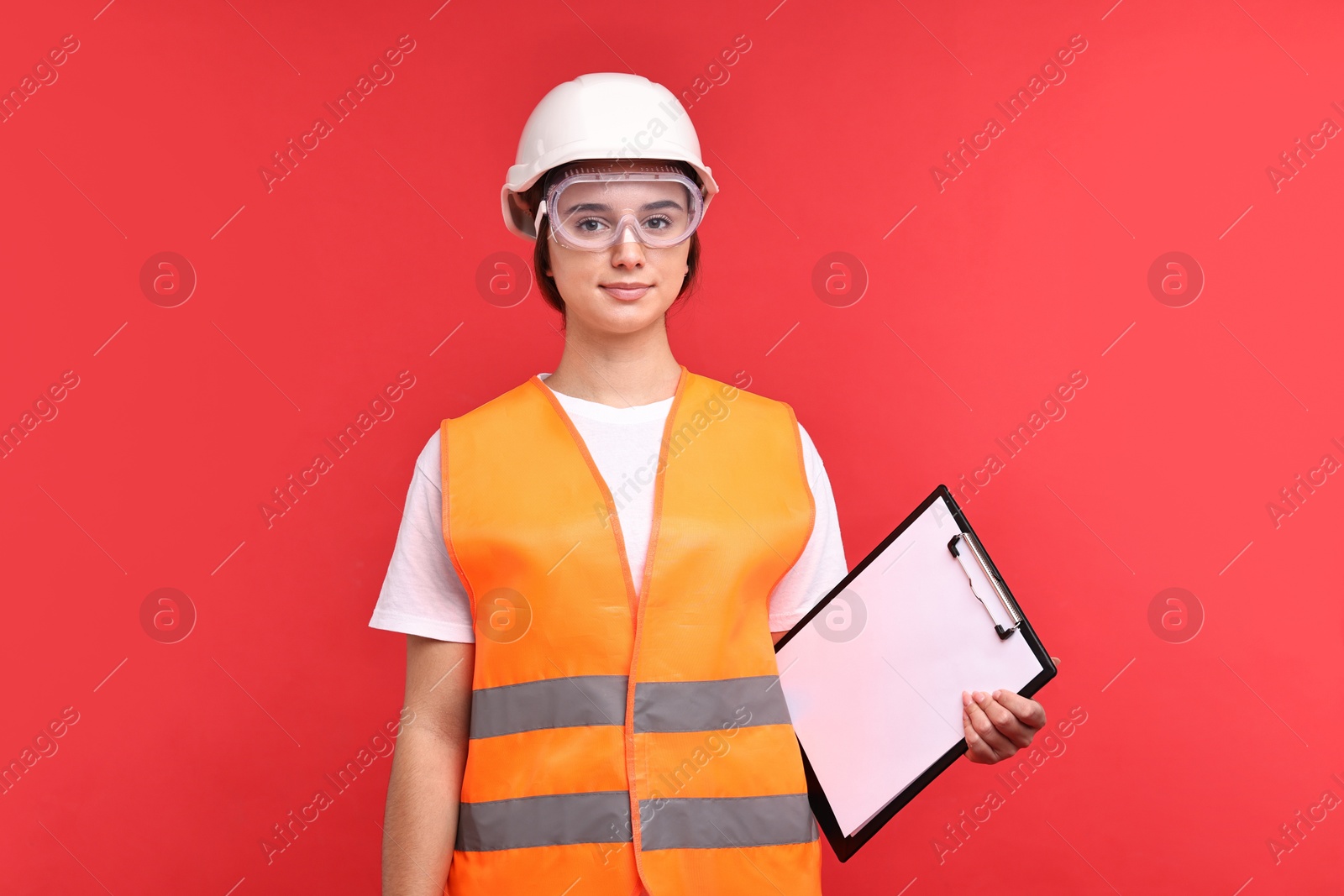 Photo of Girl with safety equipment and clipboard on red background. Work for teenagers