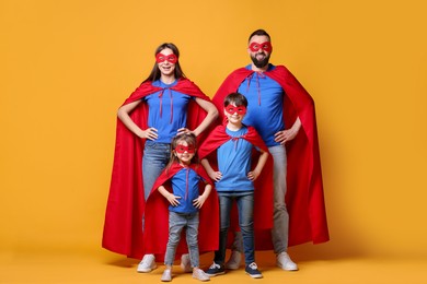 Photo of Parents and their children wearing superhero costumes on orange background