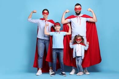 Photo of Parents and their children wearing superhero costumes on light blue background