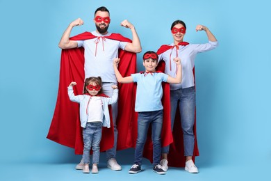 Photo of Parents and their children wearing superhero costumes on light blue background