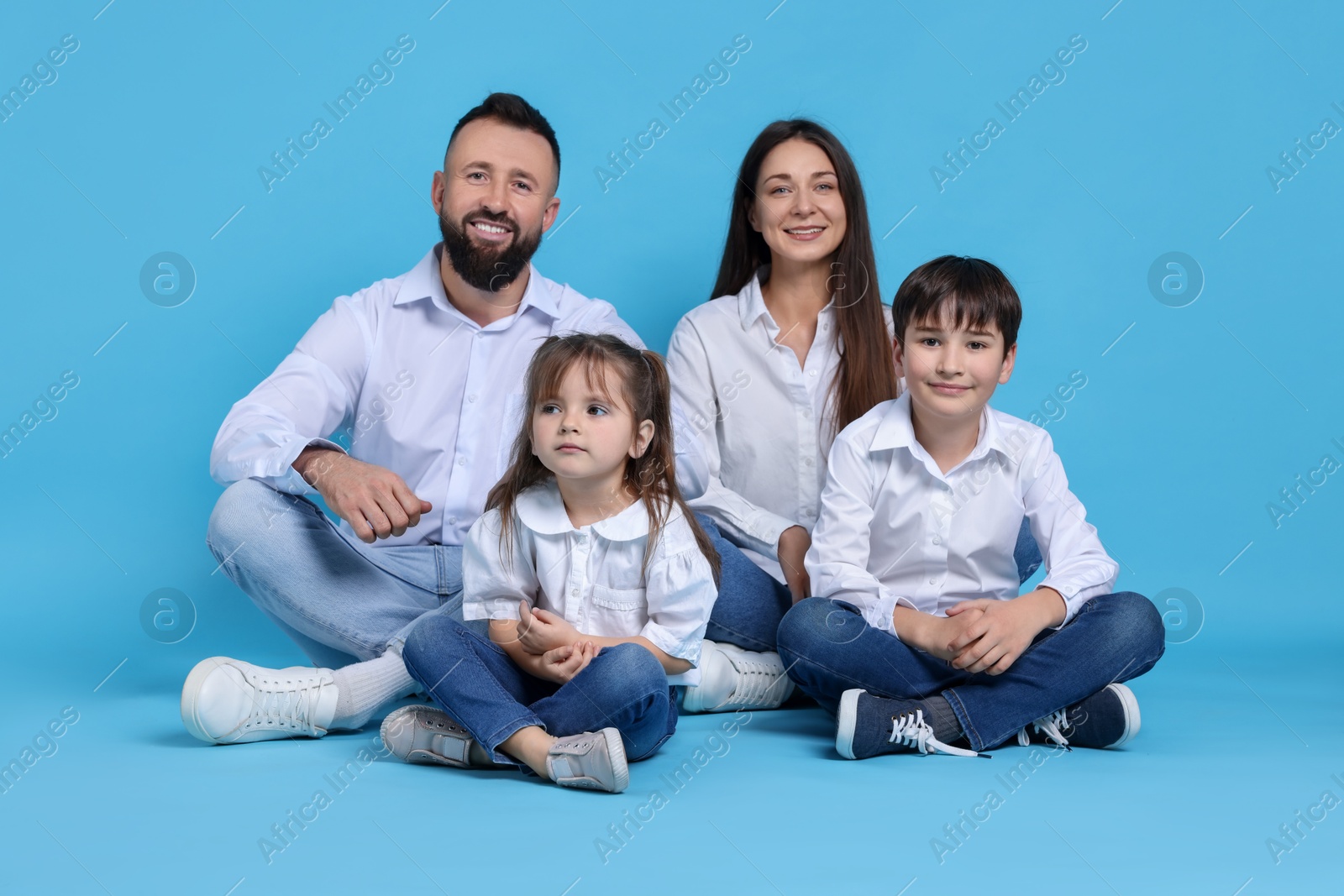 Photo of Happy parents and their children on light blue background