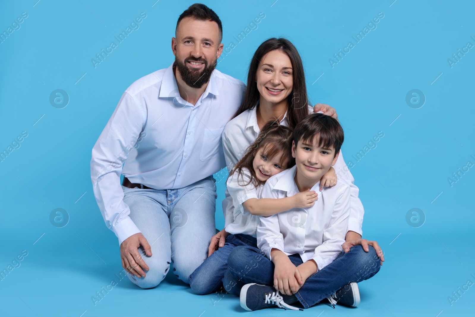 Photo of Happy parents and their children on light blue background