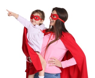 Photo of Mother and her cute little daughter in superhero costumes looking at something on white background