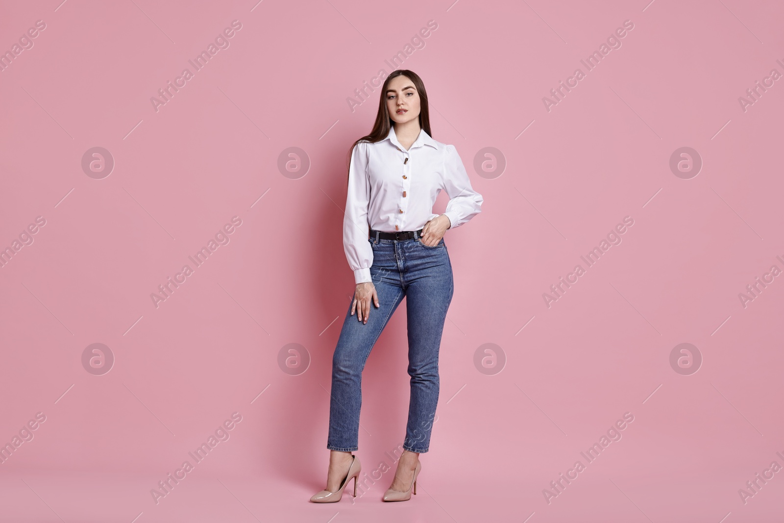 Photo of Beautiful young woman in stylish jeans on pink background